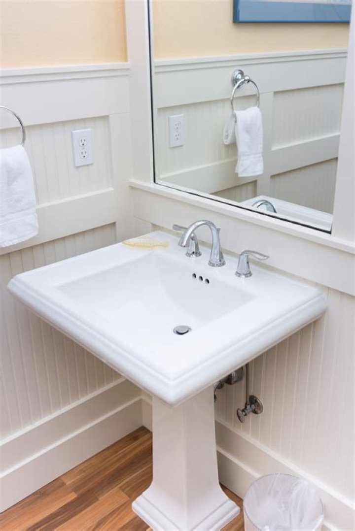How do you hide plumbing behind a pedestal sink?